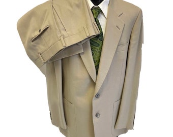 May include: A beige suit with a single-breasted blazer and matching pants. The blazer has two flap pockets and a button closure. The pants have a button fly and belt loops.