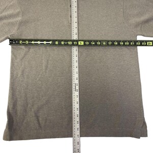 May include: A gray long-sleeved shirt with a zippered collar. The shirt is measured with a ruler, showing a length of 28 inches.