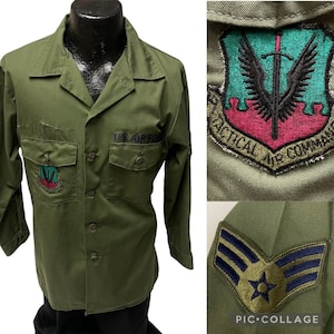 Peut inclure: Une chemise militaire verte avec un écusson US Air Force sur la poche gauche et un écusson Tactical Air Command sur la manche droite. La chemise a également un insigne de grade sur la manche gauche.