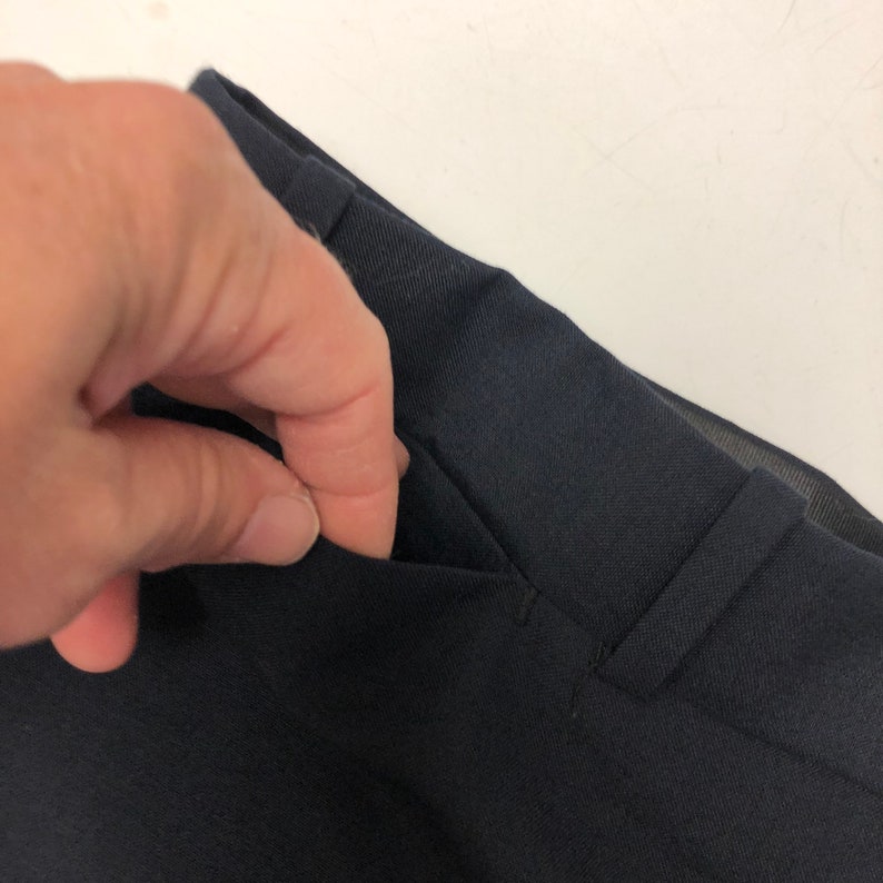 May include: Close-up of a dark blue pair of pants with a pocket on the front.