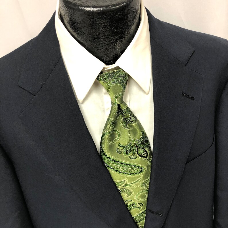 May include: A dark blue suit jacket with a white dress shirt and a green paisley patterned tie.