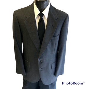 May include: A dark gray blazer with a single button closure and two additional buttons below. The blazer has a classic fit and a subtle pattern.