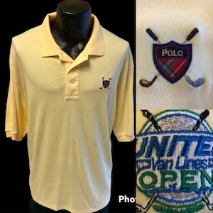 May include: A yellow polo shirt with a small embroidered logo of a shield with crossed golf clubs and the word "Polo" on it. The shirt also has a larger embroidered patch on the front that says "United Van Lines Open" with crossed golf clubs.