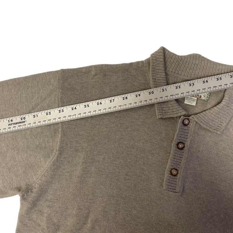 May include: A light brown long-sleeved knitted sweater with a collared neckline and a button placket. The sweater has a "Laguna" brand label.