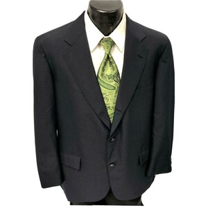 May include: A dark blue blazer with a three-button closure and a single vent in the back. The blazer has a green paisley patterned tie.