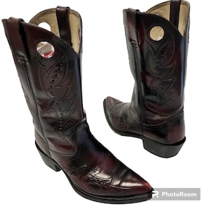 Könnte beinhalten: Ein Paar burgunderfarbene Cowboy-Stiefel aus Leder mit aufwendigen Nähten und spitzer Zehenkappe. Die Stiefel haben einen dekorativen Ausschnitt am Schaft.