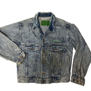 May include: A light blue denim jacket with a faded, acid wash effect. The jacket has a green and white patch on the left chest that says "Cool Breeze".