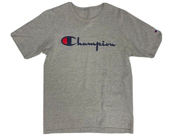 May include: A gray short-sleeved t-shirt with a navy blue and red Champion logo.