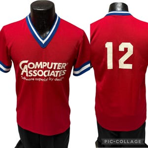 Peut inclure: Maillot rouge vintage avec bordures blanches et bleues. Le devant affiche le texte "COMPUTER ASSOCIATES Software superior by design." Le dos affiche le numéro "12" en blanc.