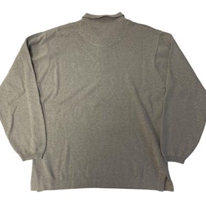 May include: A gray long-sleeved sweater with a mock neck collar.