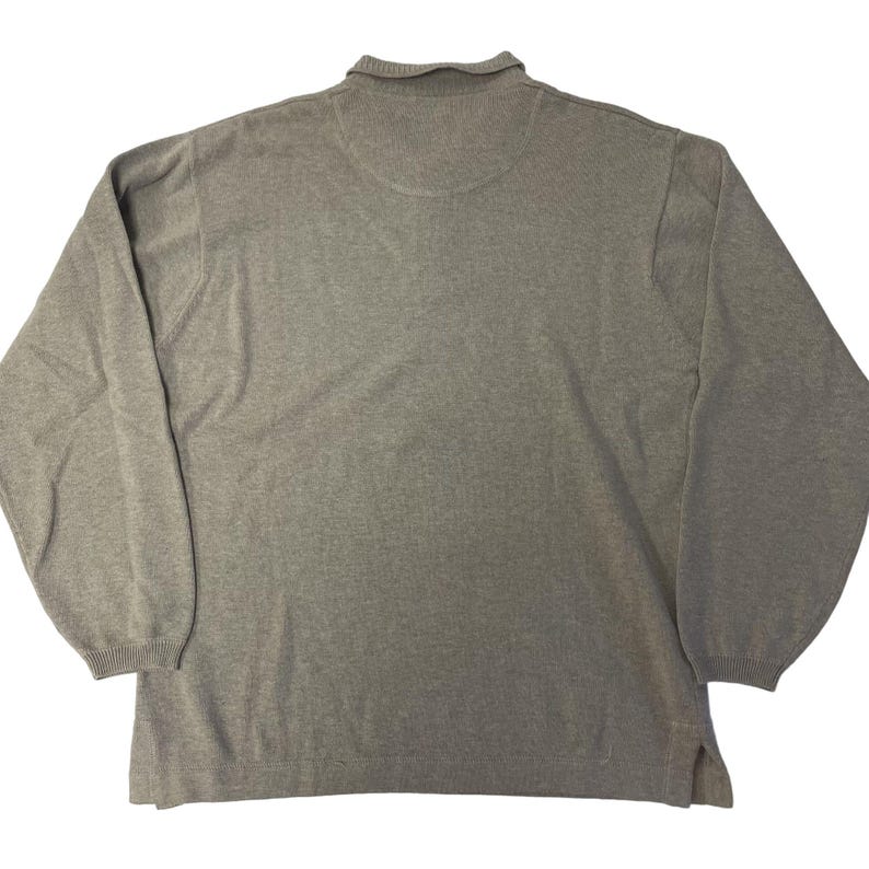 May include: A gray long-sleeved sweater with a mock neck collar.