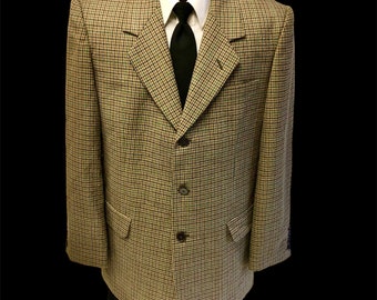 May include: A brown, black, and white plaid blazer with a black tie. The blazer has a three-button closure and two flap pockets.