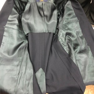 May include: The inside of a navy blue blazer with a green satin lining. The label reads "Brooks Brothers" with the text "Made in USA" underneath.