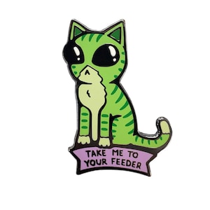 May include: Green cat with black eyes and a striped pattern sitting on a purple banner with the text "Take me to your feeder".