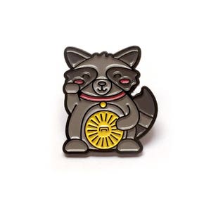 May include: A gray raccoon enamel pin with a red collar and a yellow wheel. The raccoon is in a seated position with one paw raised. The pin is on a white background.