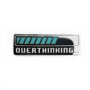 May include: A silver metal pin with a black background and a blue progress bar. The text "OVERTHINKING..." is printed in white below the progress bar.