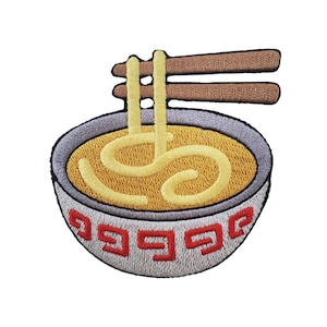May include: An embroidered patch featuring a white bowl with a red geometric pattern containing yellow noodles in broth. Two brown chopsticks are positioned horizontally across the top of the bowl, with two noodle strands extending upward.