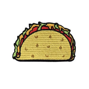 May include: A taco-shaped embroidered patch featuring a yellow shell with small brown dots, topped with green lettuce, red tomato, and yellow cheese. The entire design is outlined in a thick black border, creating a distinct and colorful graphic.