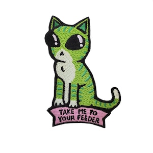 May include: Green and white embroidered iron-on patch of a cartoon cat with the text "Take me to your feeder".