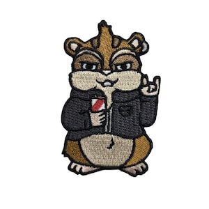 Puede incluir: Parche bordado con un chipmunk de dibujos animados con una chaqueta negra y sosteniendo una bebida roja y blanca. El chipmunk hace el gesto de rock-on. El parche tiene colores marrón, beige y negro.