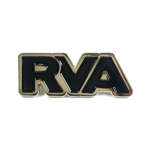 Puede incluir: Un pin de metal plateado con un diseño de esmalte negro de las letras "RVA".
