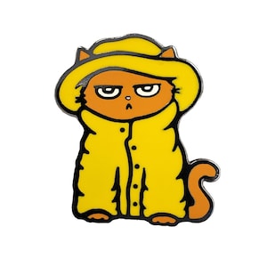 May include: A yellow cat wearing a yellow raincoat and a yellow hat with a black outline. The cat has orange fur and a grumpy expression.