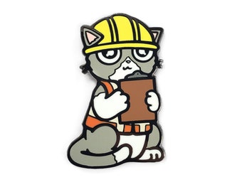 May include: A metal enamel pin featuring a gray and white cat wearing a yellow hard hat and an orange safety vest. The cat is holding a brown clipboard with both paws, displaying a focused expression with large eyes and a small mouth.