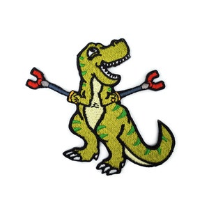 May include: Green embroidered iron-on patch of a cartoon dinosaur holding two red magnets on sticks.