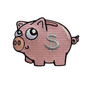 Puede incluir: Parche de cerdito rosa con una cara sonriente, ojos grandes y un signo de dólar en un lateral. El parche está bordado con detalles en blanco y negro, y una ranura en la parte superior para insertar dinero.