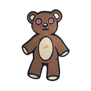 Puede incluir: Oso de peluche marrón con ojos morados y barriga beige. El oso está de pie con los brazos extendidos y tiene una sonrisa cosida.