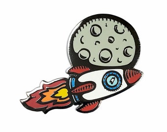 May include: A metal enamel pin featuring a white rocket ship with red fins and a blue porthole, launching into space. The rocket emits a trail of red, orange, and yellow flames, while a large, pale gray moon with dark craters sits in the background.