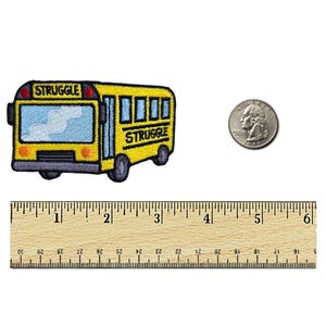 May include: A yellow school bus with the word "STRUGGLE" written on the front and back. The bus is about 2 inches long and is shown next to a ruler and a US quarter for size comparison.