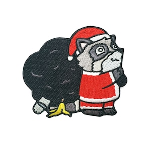 May include: Embroidered patch of a raccoon wearing a Santa hat and holding a black bag. The raccoon has a gray and white face and a black tail with a yellow banana.