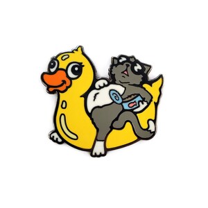 May include: A yellow rubber duck with a gray cat riding on top. The cat is wearing sunglasses and holding a can of food.
