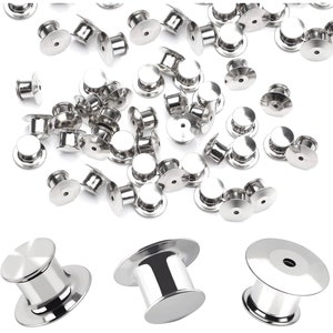 May include: A close-up of a pile of silver-toned metal safety pin backs. Three larger safety pin backs are shown separately. The pin backs are used for attaching badges, pins, and other accessories to clothing.