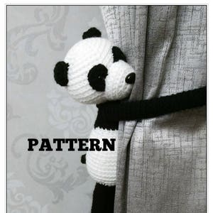 May include: A black and white crocheted panda bear curtain tieback. The panda is holding a black cord that is attached to the curtain. The text "PATTERN" is printed in black on a white background.