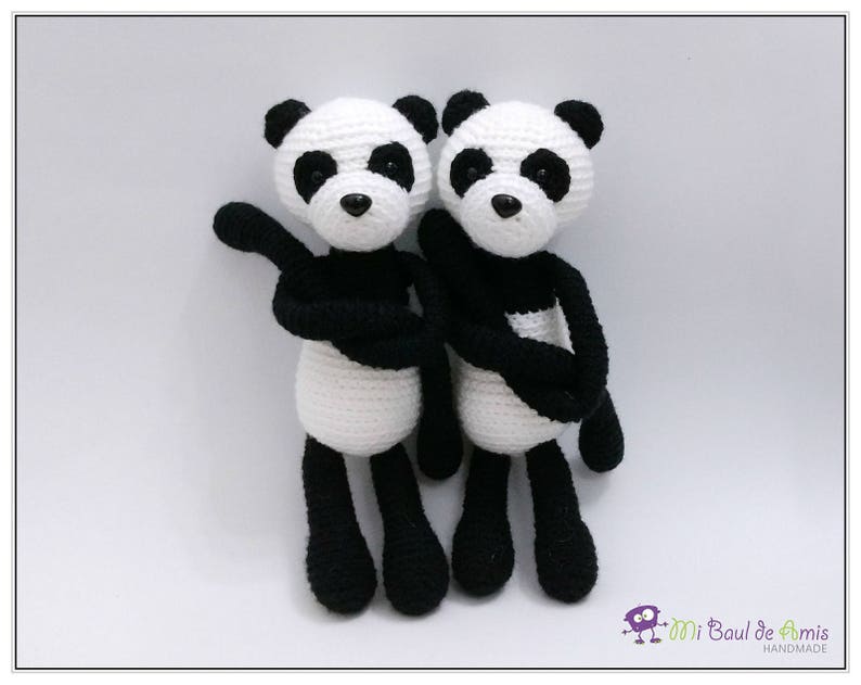 May include: Two crocheted panda bears, one black and white and the other white and black, are standing side by side. They are both wearing black crocheted scarves.