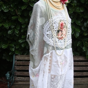 Puede incluir: Vestido verde claro con lunares blancos y superposición de encaje blanco. El vestido presenta un diseño floral y está adornado con un collar de perlas y una rosa rosa.