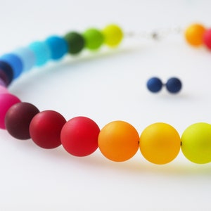Puede incluir: Un collar de cuentas de colores arco&iacute;ris con un acabado mate. Las cuentas est&aacute;n dispuestas en un degradado de morado a verde.