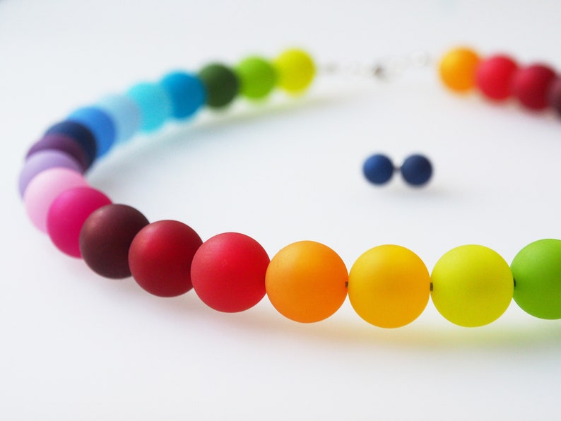 Puede incluir: Un collar de cuentas de colores arco&iacute;ris con un acabado mate. Las cuentas est&aacute;n dispuestas en un degradado de morado a verde.