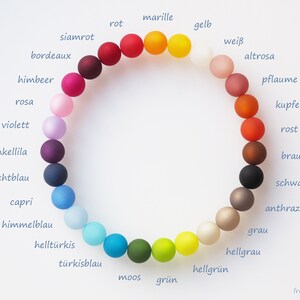 May include: A color wheel of 18 beads, each a different color, with the German name of the color written next to each bead.