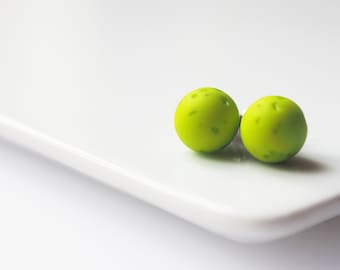 May include: A pair of lime green stud earrings. The earrings are round and have a textured surface.