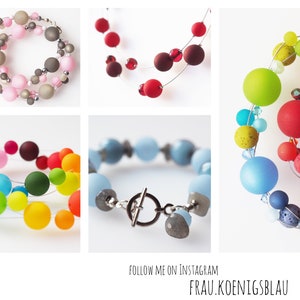 Puede incluir: Una colecci&oacute;n de collares y pulseras de cuentas de colores. Los collares presentan cuentas grandes y redondas en varios colores, incluyendo rosa, rojo, verde, azul y amarillo. Las pulseras presentan cuentas m&aacute;s peque&ntilde;as y redondas en tonos de azul y gris.