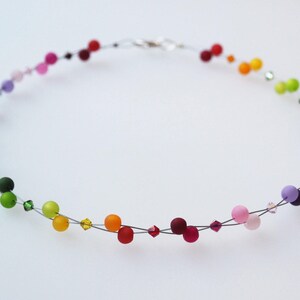 May include: A rainbow colored beaded necklace with small crystal accents. The necklace is made of wire and features a variety of colors, including red, orange, yellow, green, blue, indigo, and violet.