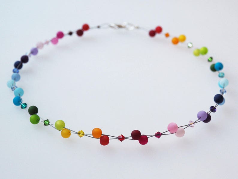 May include: A rainbow colored beaded necklace with small crystal accents. The necklace is made of wire and features a variety of colors, including red, orange, yellow, green, blue, indigo, and violet.