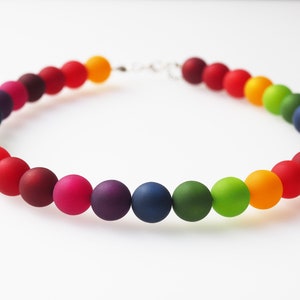 Op de afbeelding: Een regenboogkleurige kralenketting met matte kralen. De ketting is gemaakt van ronde kralen in tinten rood, oranje, geel, groen, blauw, indigo en violet.