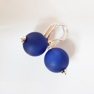 May include: A pair of blue ball earrings with silver hooks.