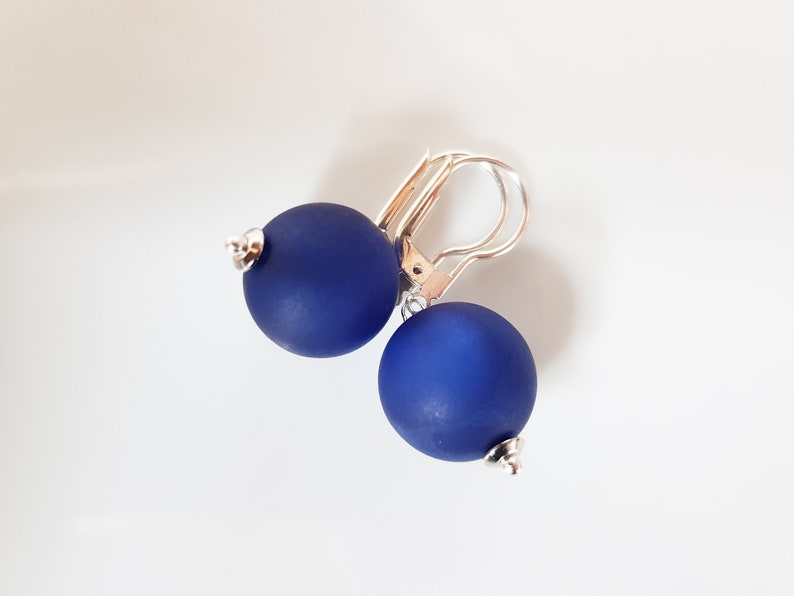 May include: A pair of blue ball earrings with silver hooks.