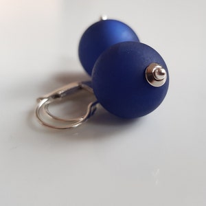 May include: A pair of blue glass ball earrings with silver hooks.