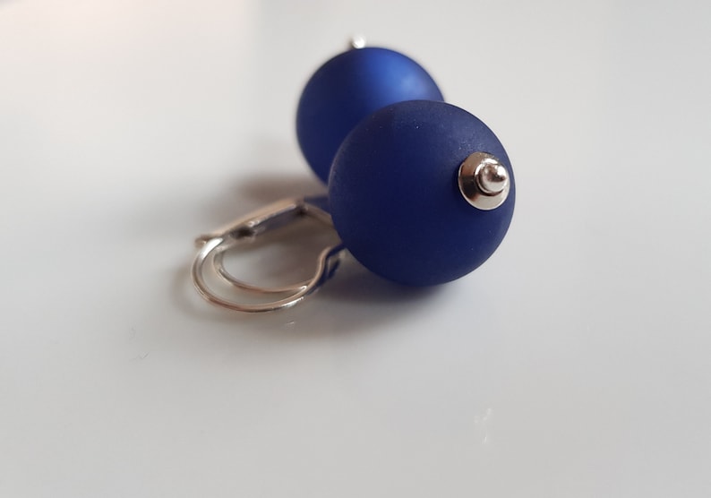 May include: A pair of blue glass ball earrings with silver hooks.